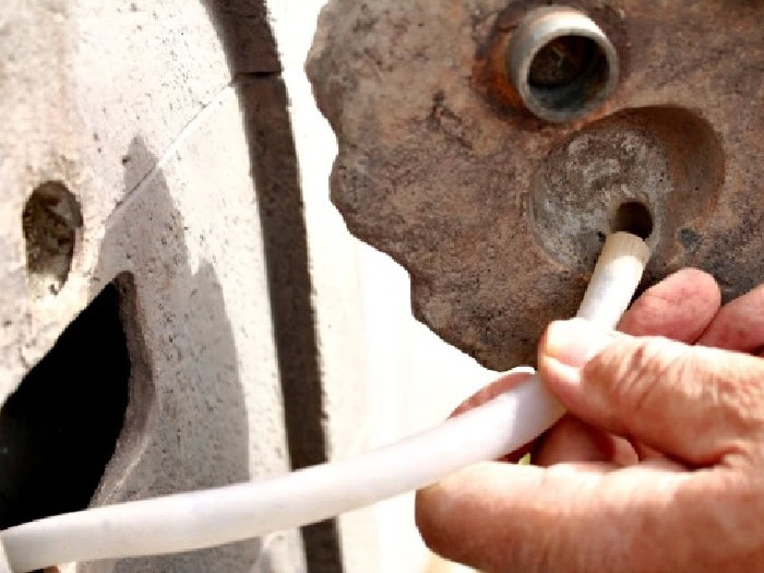 Placing the clear hose inside the fountain during the DIY water fountain repair.