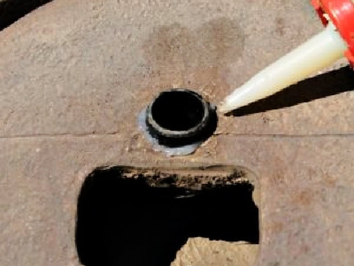 Applying silicone to secure the plastic pipe during the DIY 0water fountain repair.