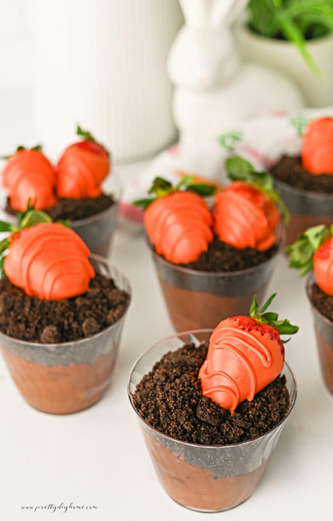 Chocolate pudding Easter dirt cups topped with Oreo crumbs and strawberry carrots.