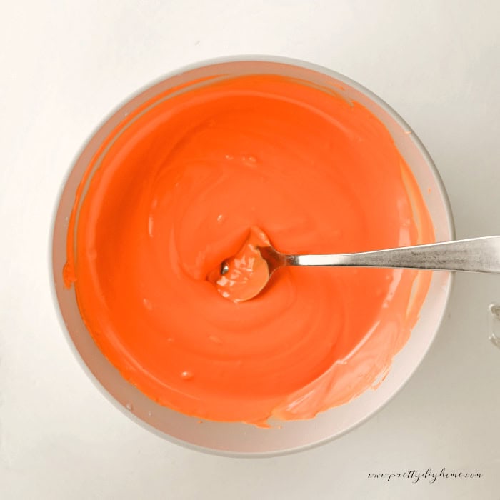 Orange candy melts in a bowl that have been melted for making strawberry carrot toppers for Easter dirt cups.