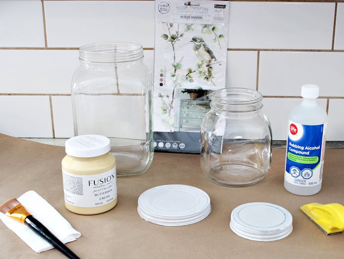 Painted jar supplies including clean jars, primed lid, paint, transfers, and tools.