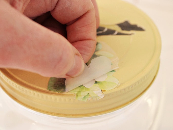 Closeup of removing transfer backing from painted jar lid showing fine detail.