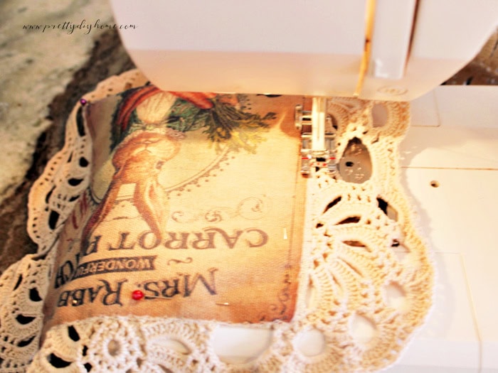 Sewing the printed bunny panel onto a crochet doily for the DIY bunny wall pocket.