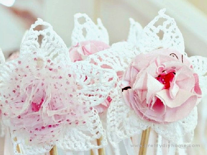 Two white crochet stars with fabric flowers on top and button centers.