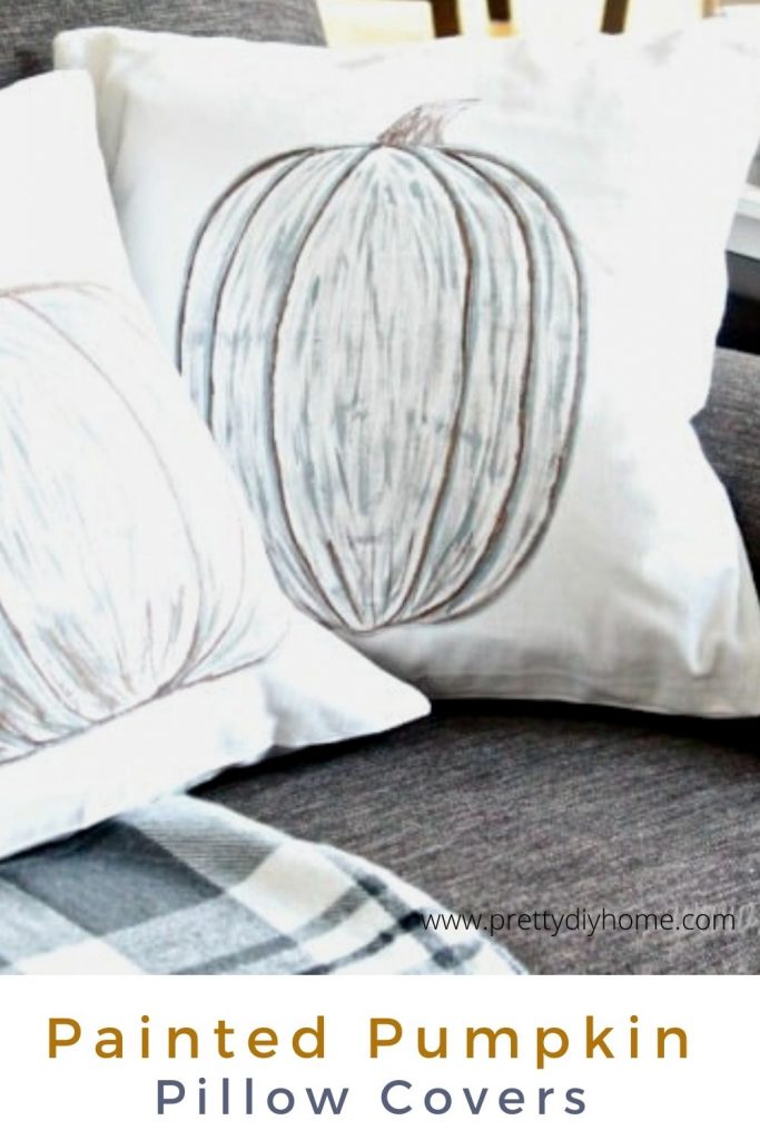 A white pillow cover with neutral hand painted pumpkin.