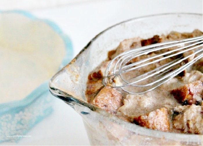 A large mixing bowl filled with ingredients for making pumpkin bread pudding.