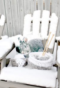 Two small wool baskets sitting on an outside chair for pretty winter decor. The baskets are made using a free pattern.