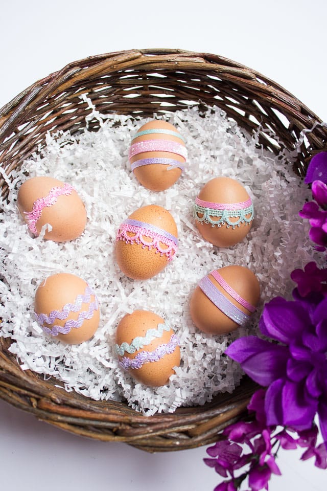 A Easter backet with seven brown Easter eggs decorated with ribbon in ipretty pastel colors.