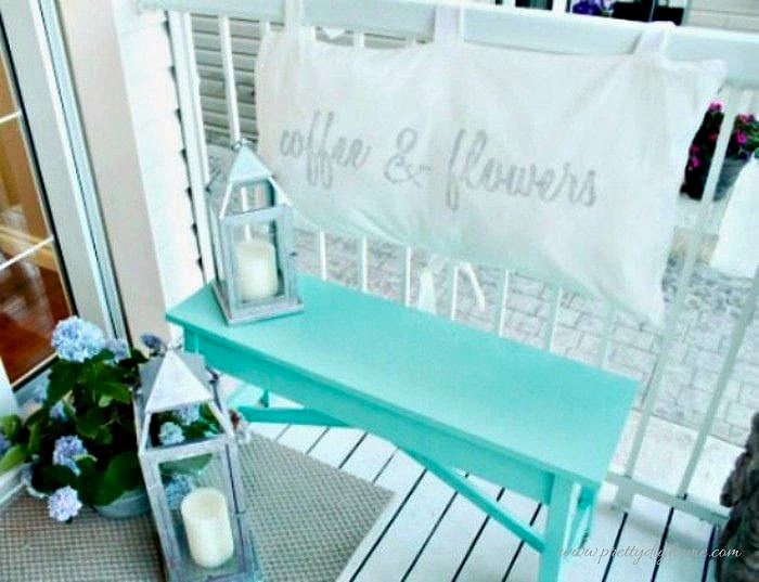 Bright front porch detail with a painted bench, cushion back, and simple outdoor decor.