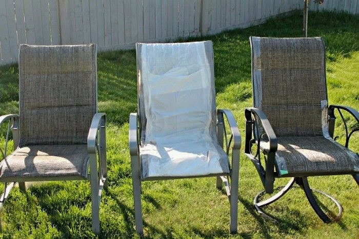 This image shows the patio chairs before repainting, with the fabric taped and covered for preparation.