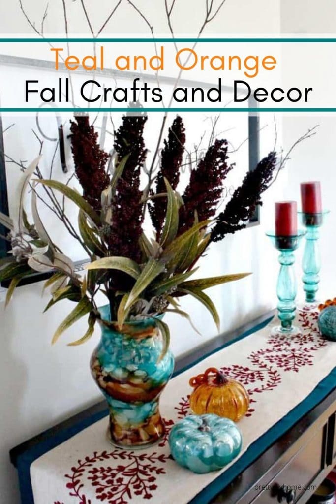 A tall vase on a front foyer table with DIY Fall candles, flower arrangements, and handmade table runners.
