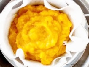 Pumpkin puree straining over a bowl in the sink to thicken it.