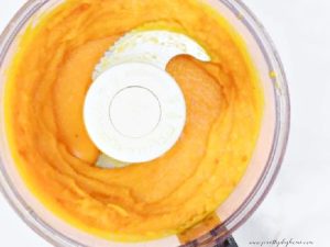 Moist fresh cooked pumpkin being pureed in a food processor.