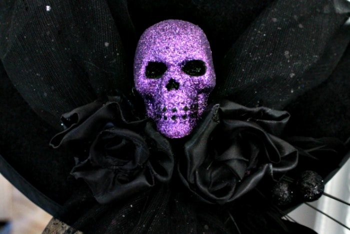 Black satin roses and a skull on the back of a DIY witches hat. DIY witch hat, witch hat decoration ideas, hat witch designs