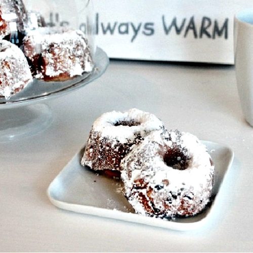 A traditional recipe for Gugelhupf Christmas cake served in individual sizes. There are two gugelhupf cakes sitting on a white plate.