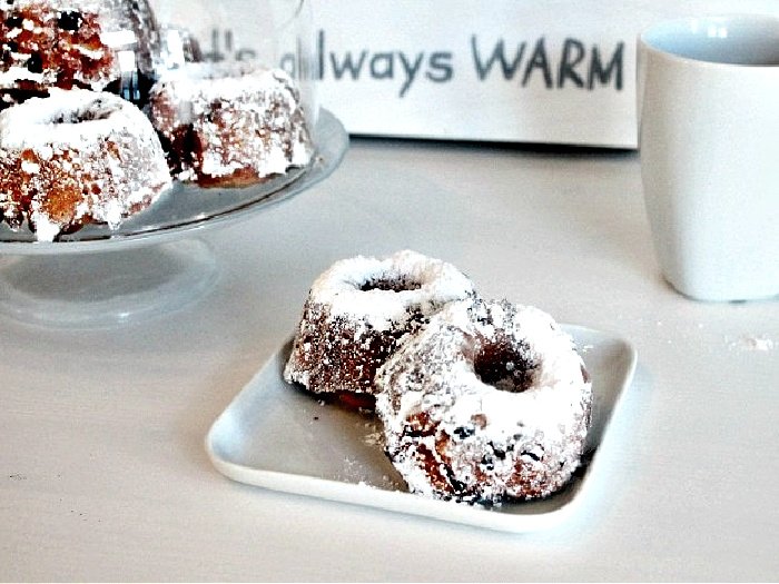 A traditional recipe for Gugelhupf Christmas cake served in individual sizes.  There are two gugelhupf cakes sitting on a white plate.  