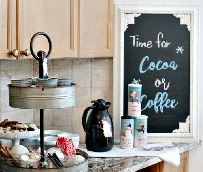 Christmas coffee and cocoa bar with chalkboard sign, coffee carafe, and tiered tray of treats.