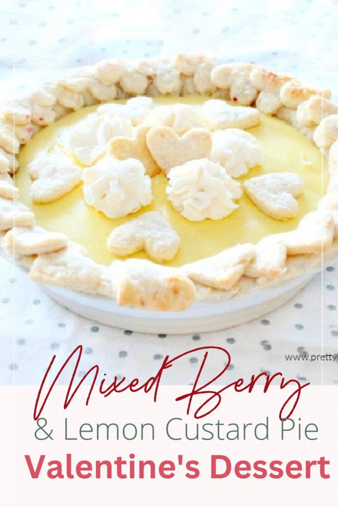 A mixed berry pie with lemon custard on top and dressed up as a Valentines dessert with sugary hearts and whipping cream on top.