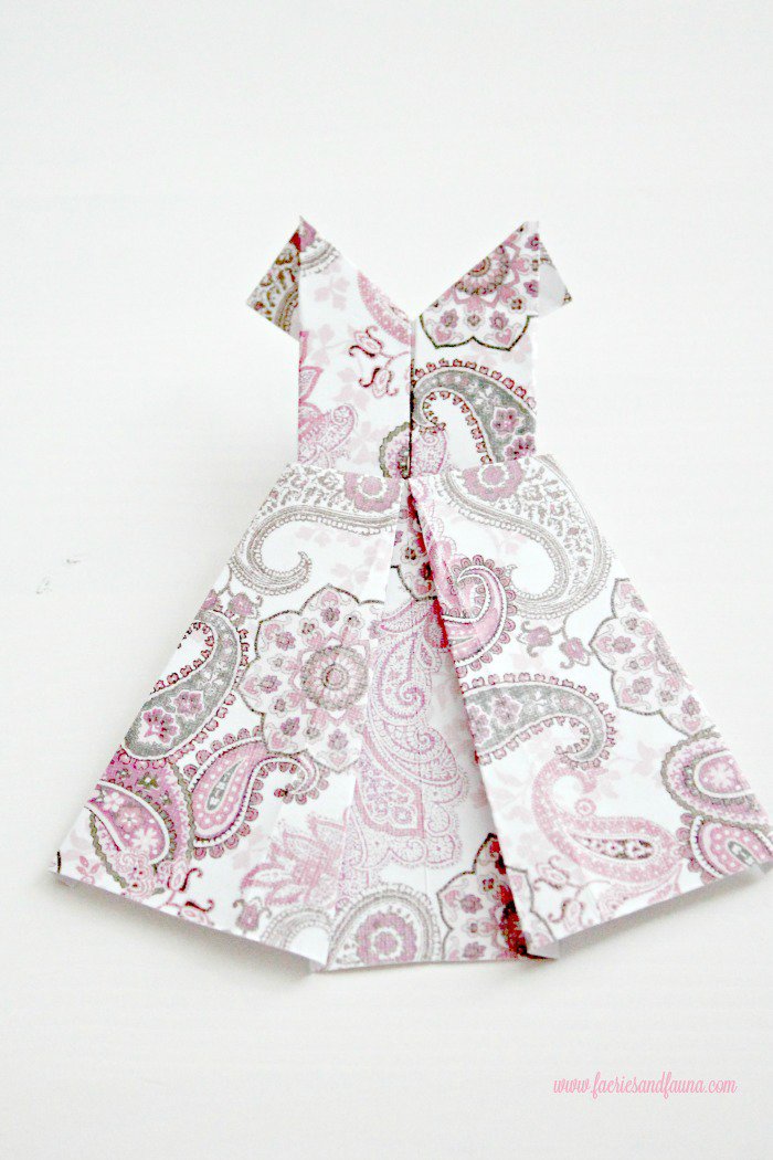 Close up picture of a paisley patterned pink scrap paper origami dress. DIY paper banner, paper dress banner, paper dress design, spring banner, DIY spring decor, paper home decor, paper dress, banner