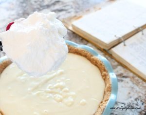 A large scoop of fluffy white meringue topping being placed on a vanilla custard filling.