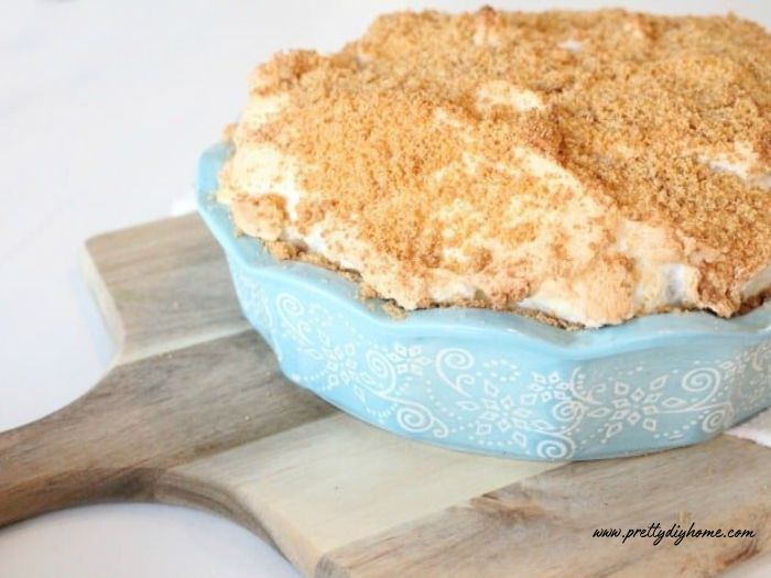 A large freshly made flapper pie recipe with vanilla cream filling, graham cracker crumbs on top and a thick layer of golden brown meringue.