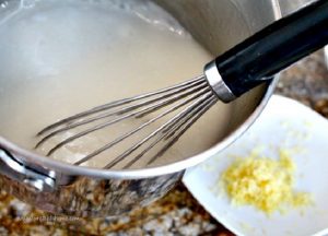 A saucepan with a whisk blending the ingredients for lemon pie filling.