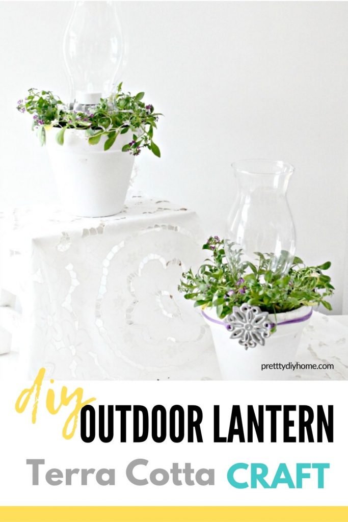 A set of white DIY lanterns made using dollar store clay pots, white paint, glass lantern covers and real plants.