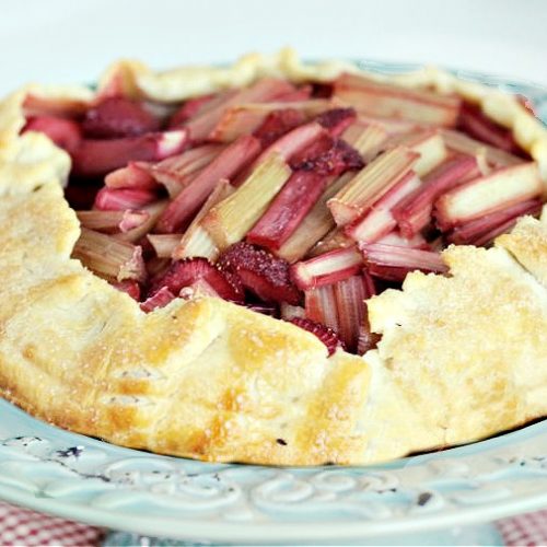 A large rustic strawberry rhubarb pie with an open top, and golden sugar topped crust.