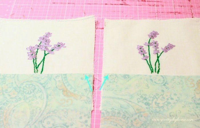 Aligning blue fabric over embroidered lavender sachet front pieces.