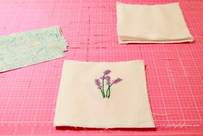 Assembling lavender sachet pieces with embroidered front folded and fabric layers prepared.