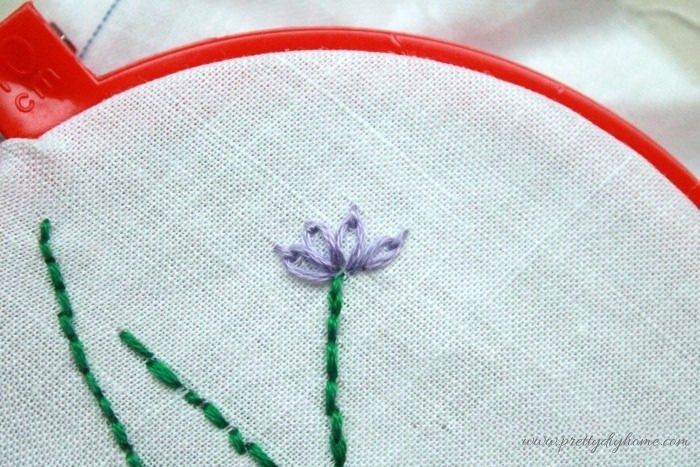 Group of four lazy daisy stitches forming a lavender blossom.