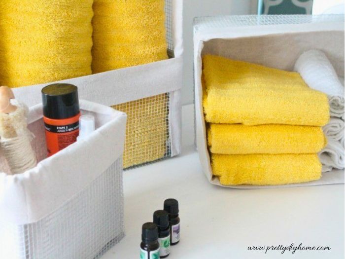 DIY wire baskets with fabric liners are used to organize towels and small items on a countertop.