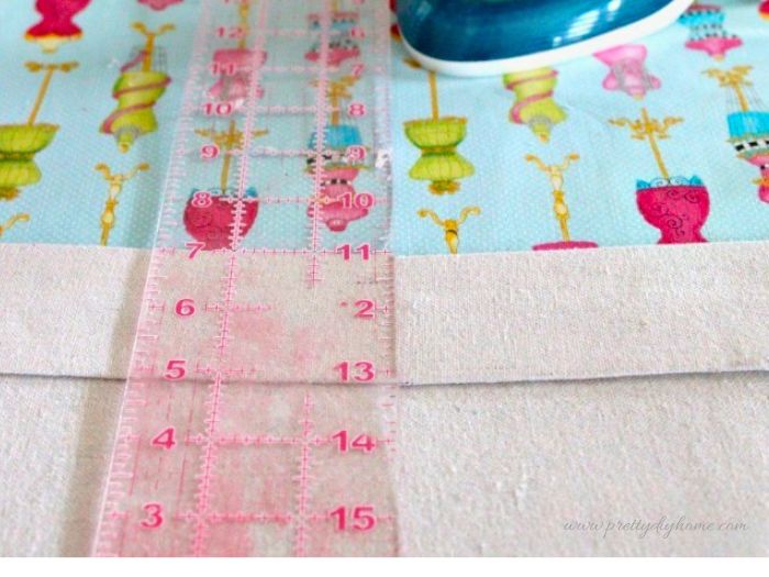 The top edge of the fabric liner is folded over about two inches and measured before pressing.