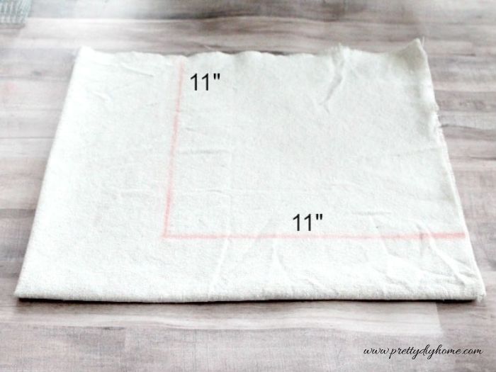 Fabric is folded and marked to measure an 11 inch square for cutting the corners of a basket liner.