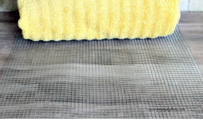 A rolled towel is placed on wire mesh to help measure the size for a DIY wire basket.