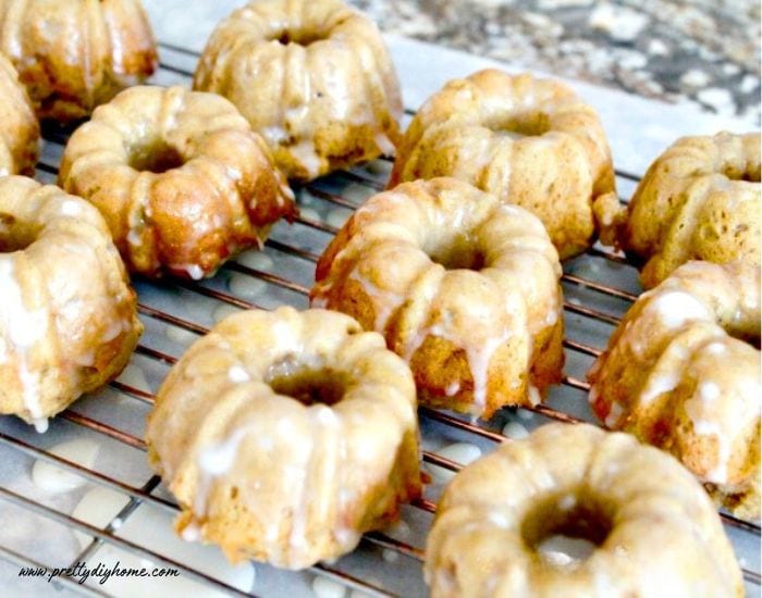 A tray of baked pumpkin donuts cooling with vanilla glaze on top.