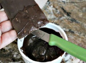 Placing melted chocolate onto solid chocolate to help it adhere to a chocolate cheesecake while making a chocolate cake collar