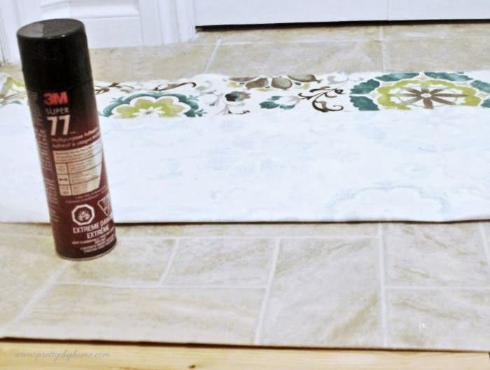 A DIY pet feeding mat setup with fabric laid over linoleum and spray adhesive ready for use.