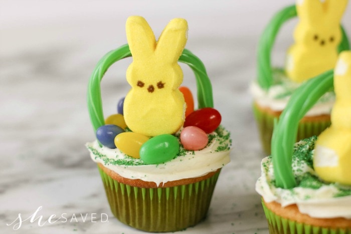 A Easter basket cupcake recipe topped with frosting, jelly beans and a peep Easter bunny.