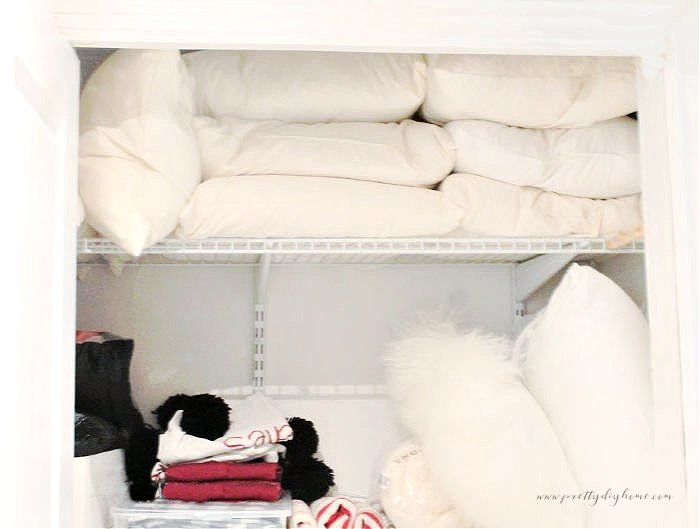 The top two shelves of a closet filled with old pillows.  