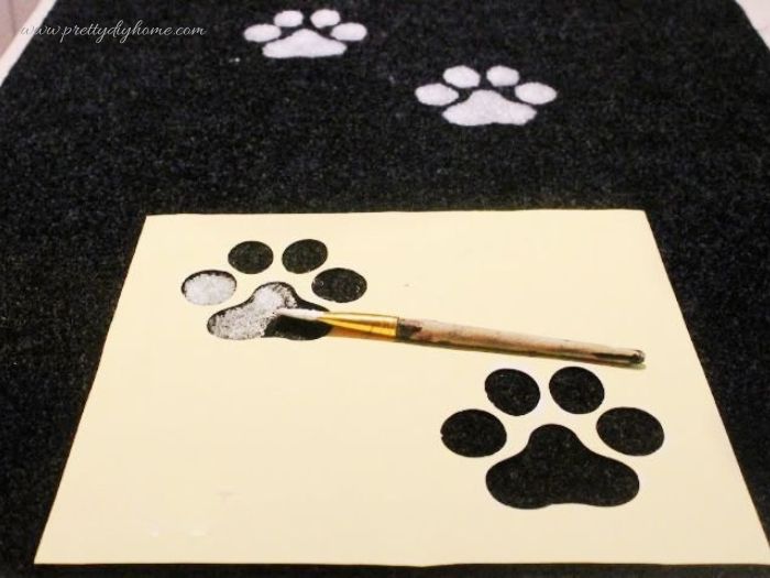 Painting paw prints on carpet using a stencil on a DIY dog ramp or pet ramp.
