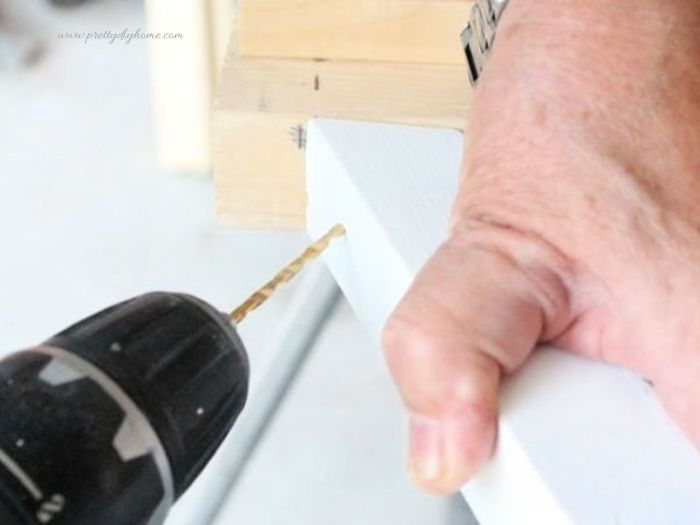 Predrilling screws into the side rails of a frame for a DIY dog ramp.