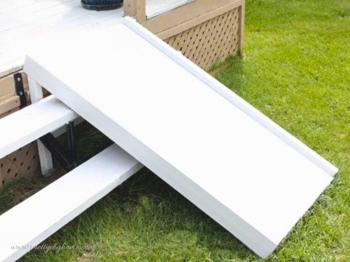Painted DIY dog ramp installed over stairs before adding carpet and paw prints.