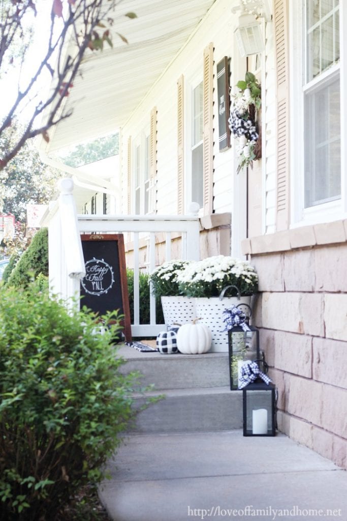 black and white fall decor for the front porch including white moms, white olive baskets, black and white Fall chalkboard and buffalo plaid pumpkins.