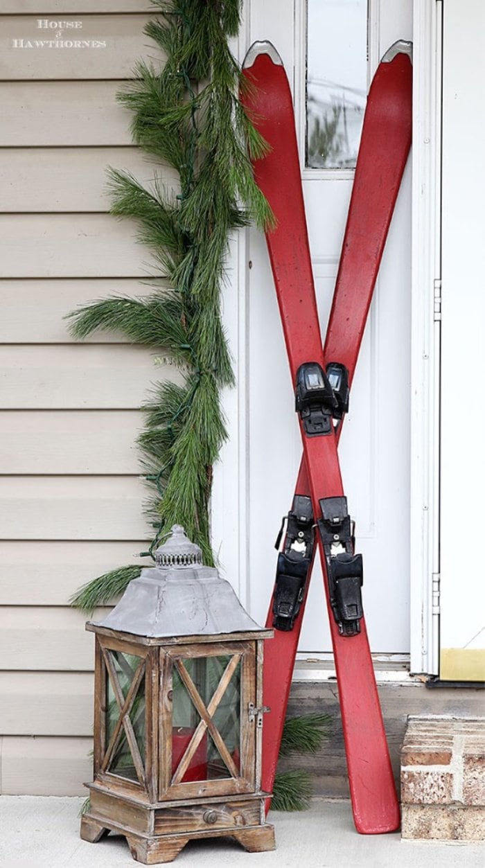 Christmas front porch decorated with vintage outdoor Christmas skiis painted in bright red.