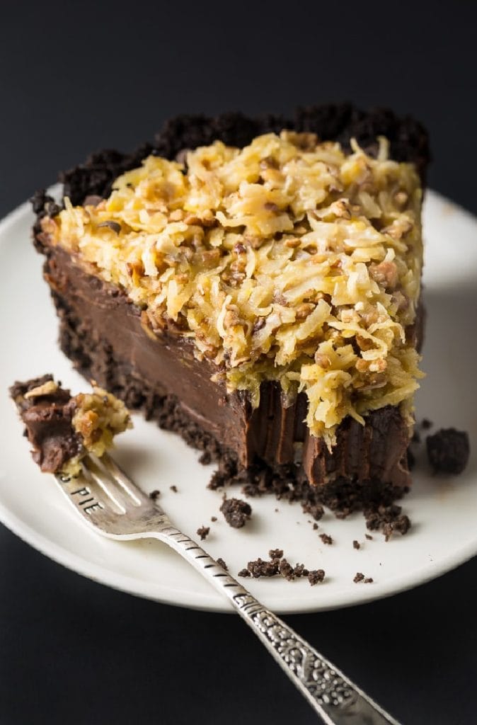 A thick slice of gerrman chocolate pie, you can see the layers including a very thick chocolate filling with a golden crunchy topping with loads of toasted coconut.