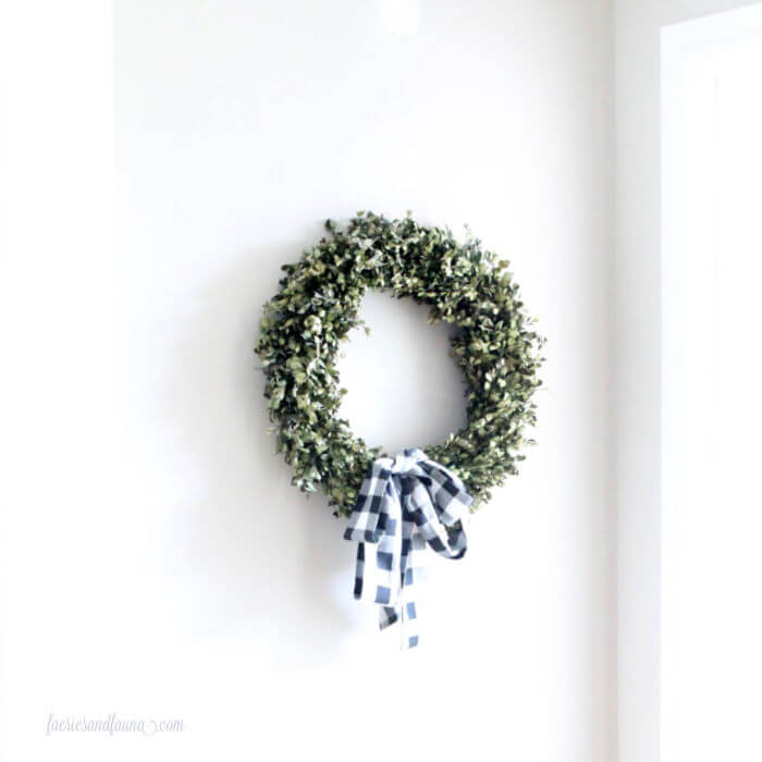 A wreath hanging on the wall before it has a backdrop