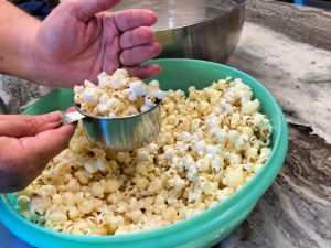 Popcorn being measured while transferring to a second bowl for popcorn ball recipe.