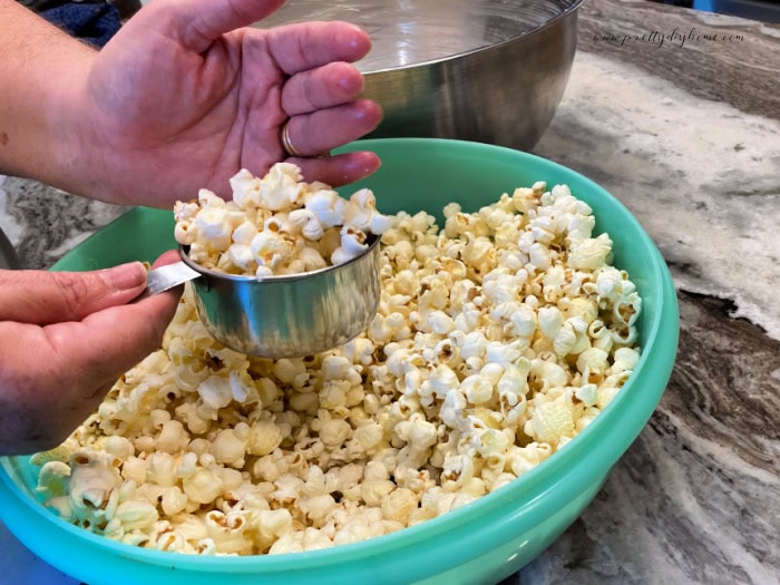 Popcorn being measured while transferring to a second bowl for popcorn ball recipe.