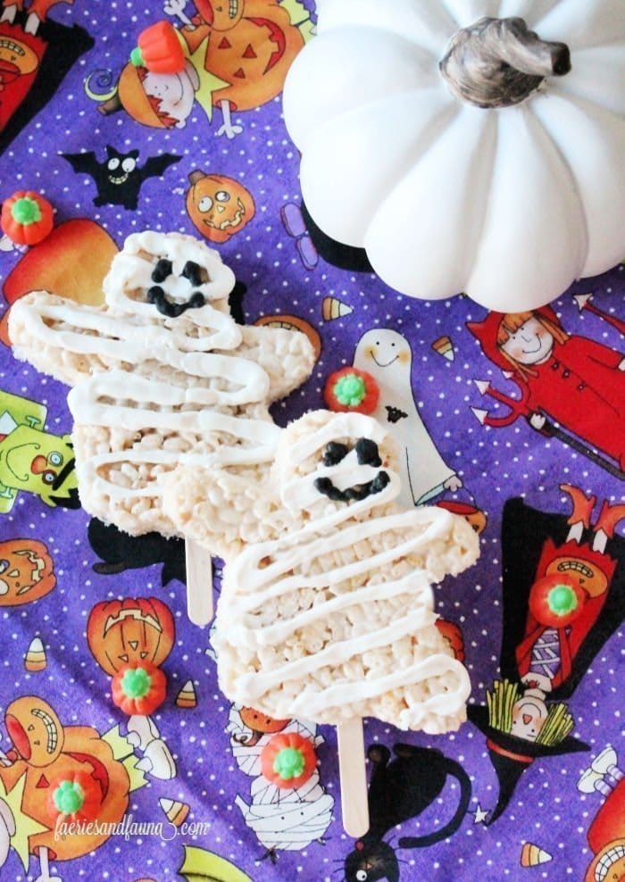 Two cute mummy rice krispie treats on sticks with smiling faces.